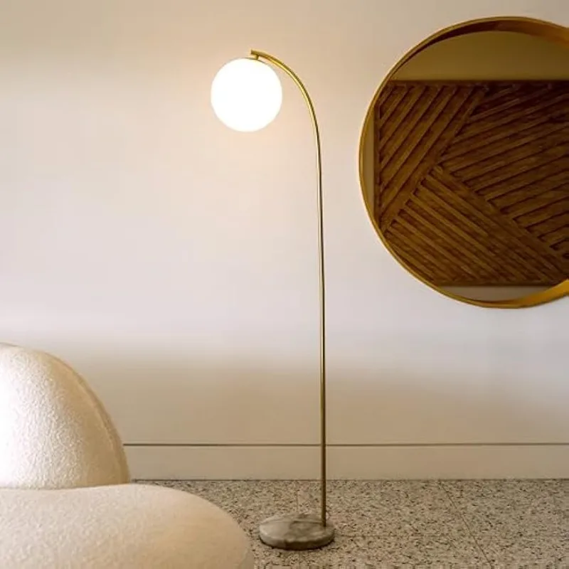 Modern LED arc floor lamp with frosted glass shade in a mid-century inspired setting